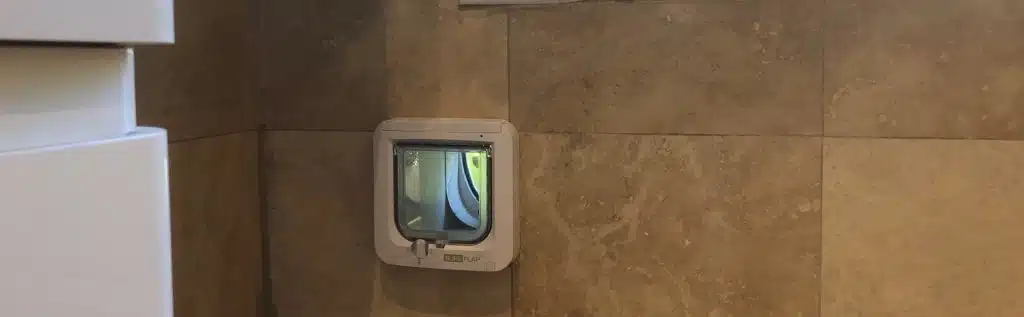 SureFlap microchip-activated cat flap expertly installed in an external bathroom wall. Fitted on to exciting, brown marble effect tiles.