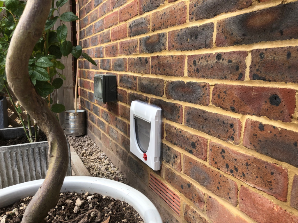 Cat flap fitted in burnt-cinder-effect brick wall