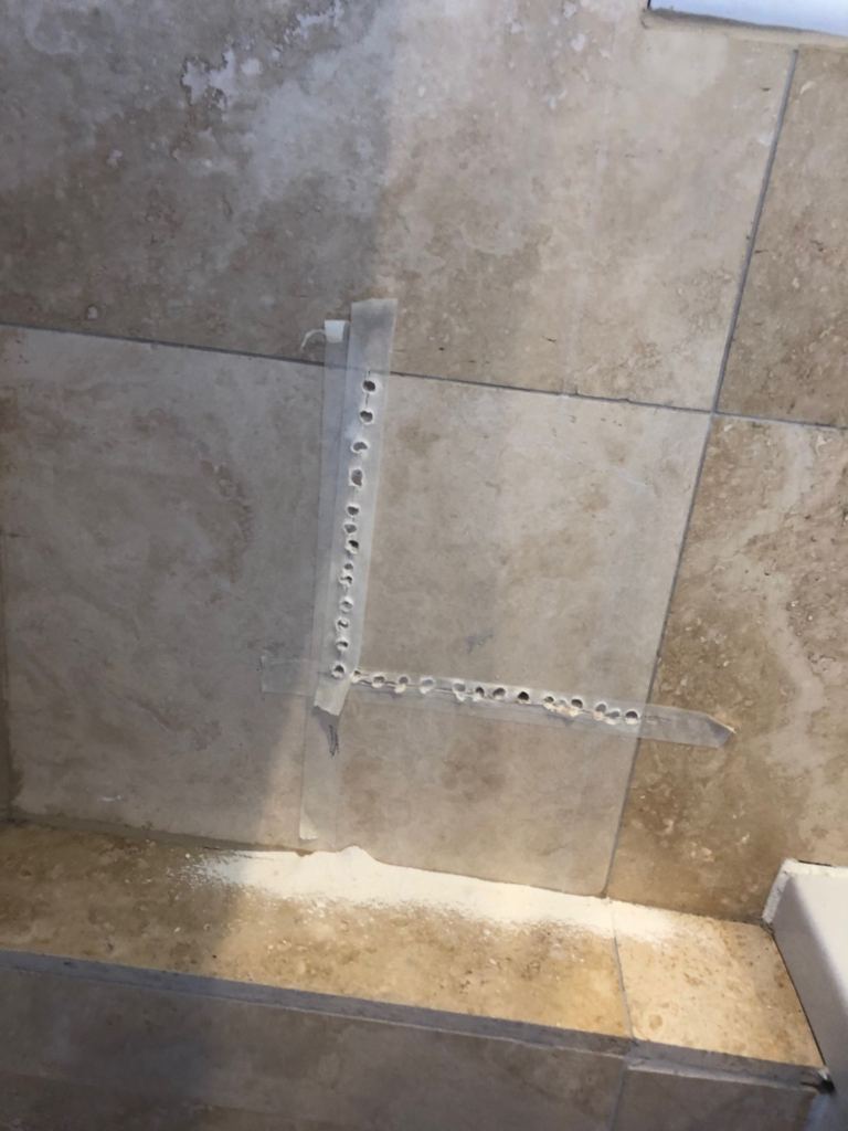 Tiled wall with masking tape clearly showing. holes drilled horizontally and virtually  