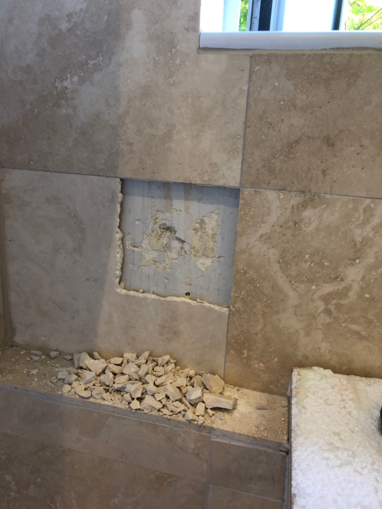 Tile with a square hole cut-out, showing the plastered wall behind 