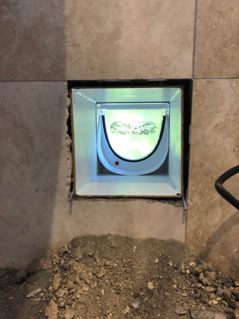 close-up of a wall liner fitted in a wall, with a cat flap fitted to the external wall. using M4 threaded rods