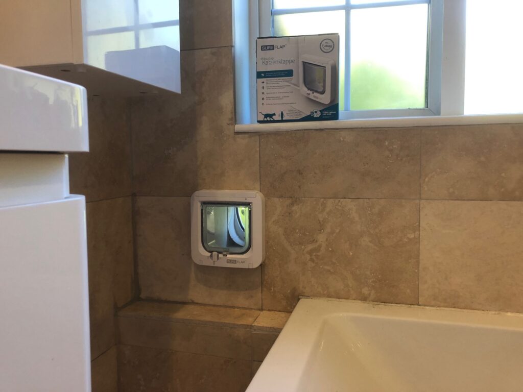 Microchip-activated cat flap in beige-marble-effect, bathroom tiled wall